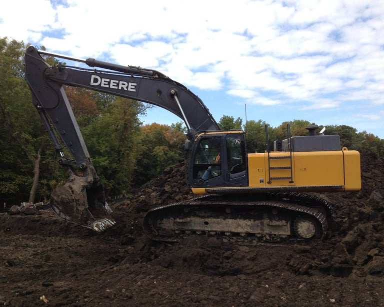 John Deere Excavator digging up dirt