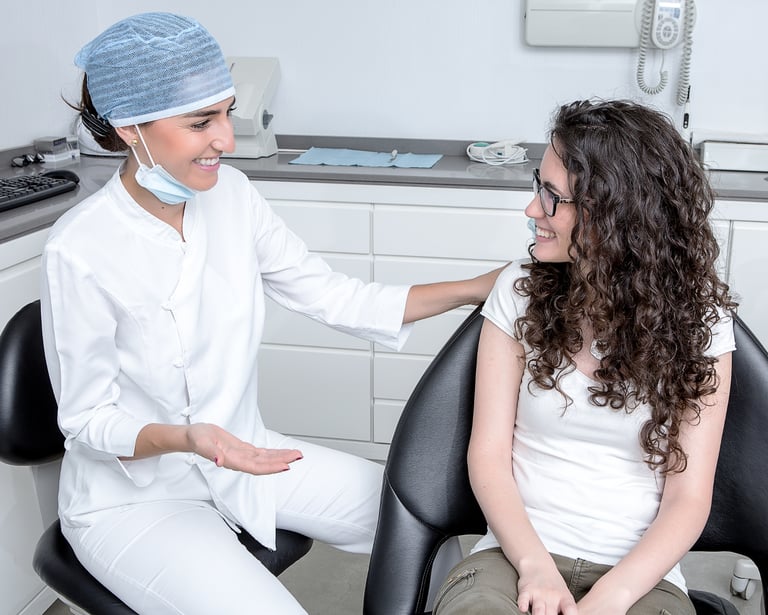 una mujer con camisa blanca y un dentista con bata blanca en una clínica dental