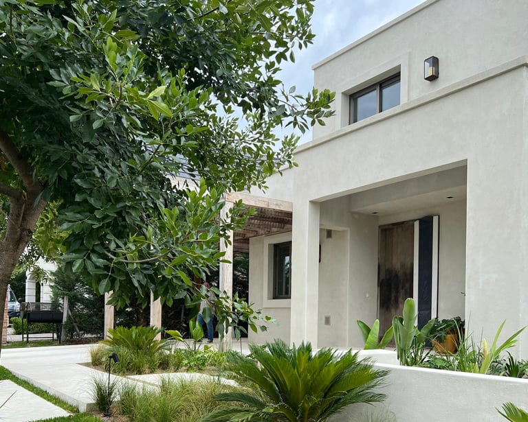 a house with a white wall and a tree in the background