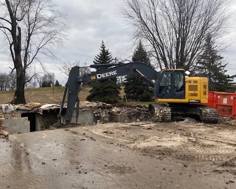 John Deere excavator digging up home from demolition project