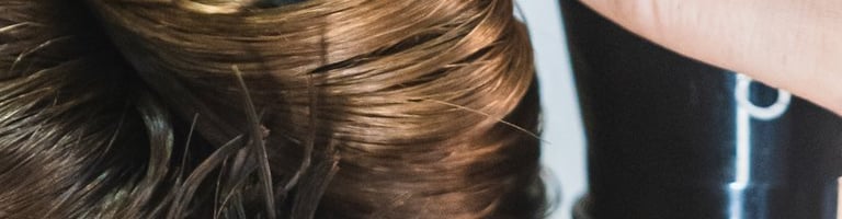 a woman is blow drying her hair in a salon