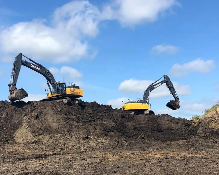 two excavators digging dirt on hill