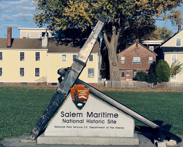 a large metal anchor on a grassy field with a sign saying salem maritime national historic site