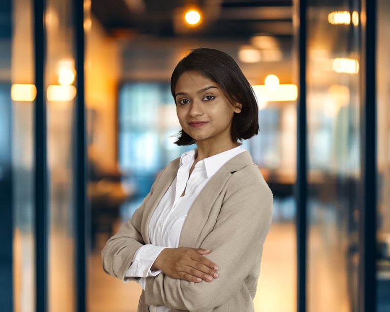 Professional businesswoman in a beige blazer standing with arms crossed in a modern office.