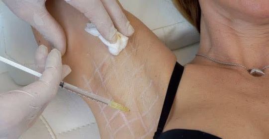 a woman in a brailler and gloves is getting her arm wrapped in a