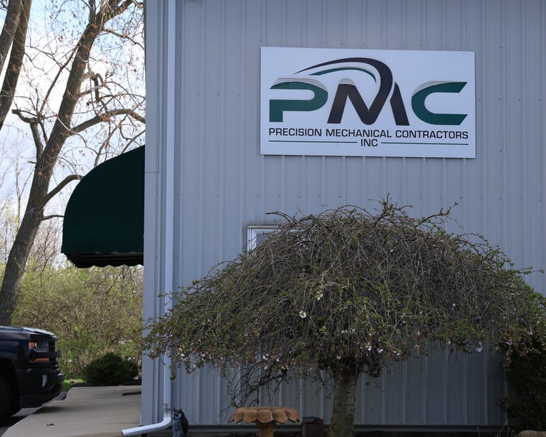 Exterior of Precision Mechanical Contractors Inc building with signage and landscaping.