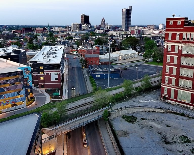 Aerial view of Fort Wayne Indiana downtown skyline with red brick buildings and city streets at dusk.