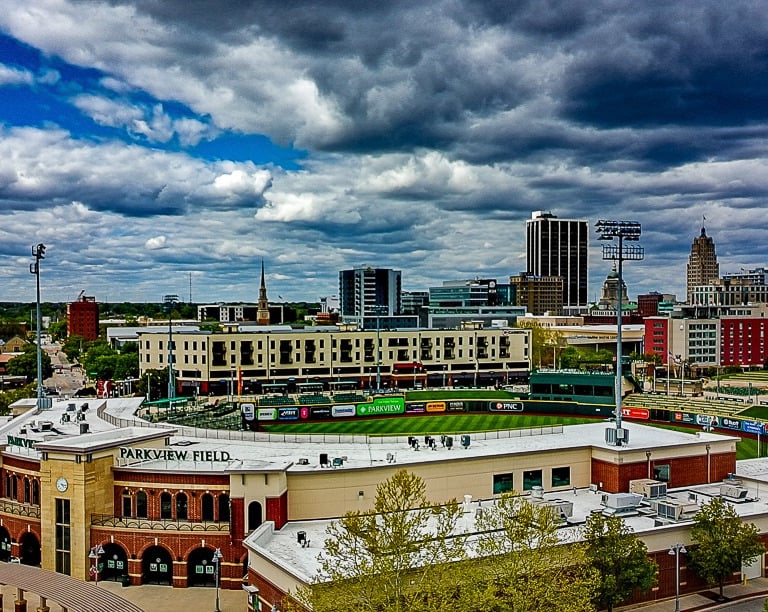 Parkview Field minor league baseball stadium in downtown Fort Wayne, Indiana under a dramatic cloudy sky.