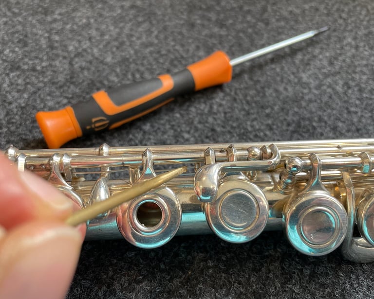 gros plan sur une main tenant un outils pour entretenir une flûte traversière