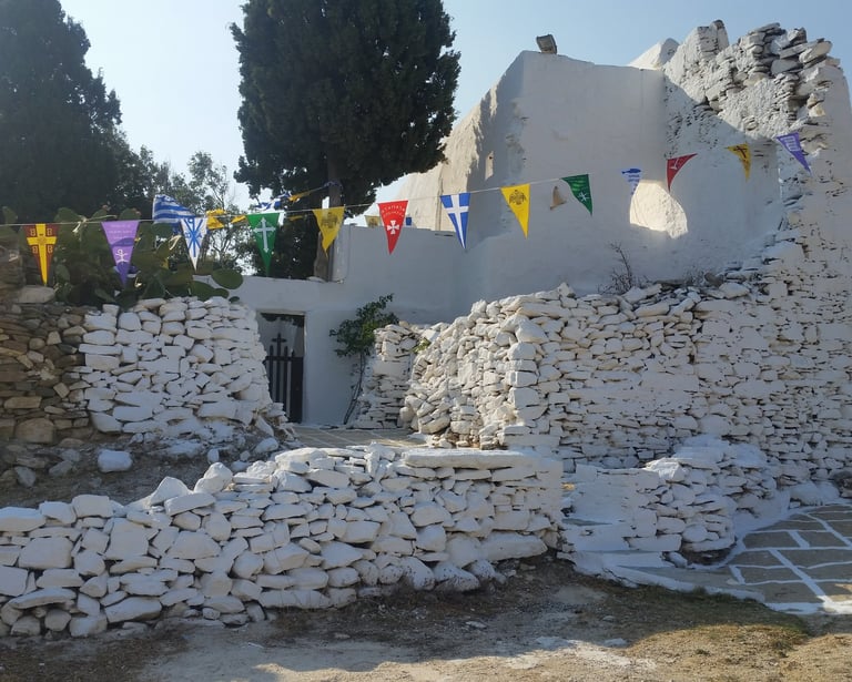 aA whitewashed chapel within a  stone wall with celebration flags 