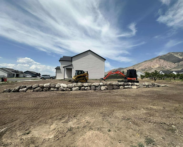 Boulder retaining wall with skid steer and mini excavator sitting idle