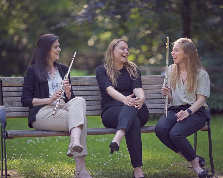 three women sitting on a bench in a park