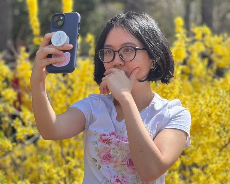 Annielou Bandong taking a photo of herself surrounded by yellow flowers on a bright sunny day.