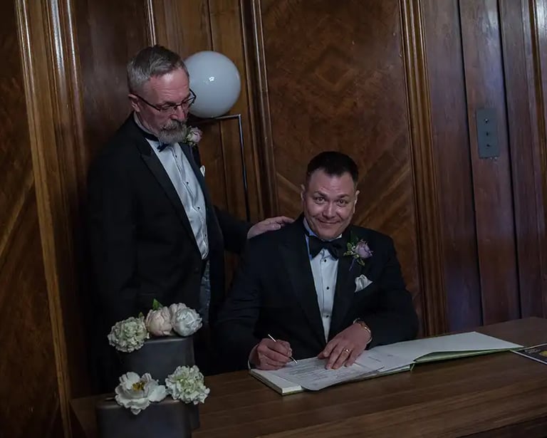 newly-weds signing the register in the paddington room at old marylebone town hall
