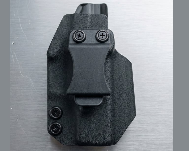 Black Kydex gun holster with a single belt clip and two retention screws, designed for concealed carry, shown on a metallic