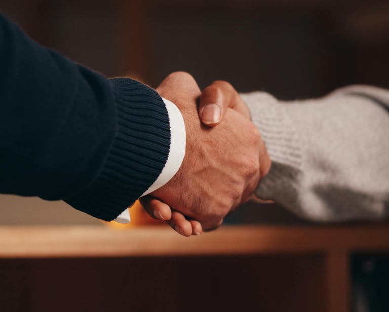 Close-up of a firm professional handshake between two business partners in an office setting.