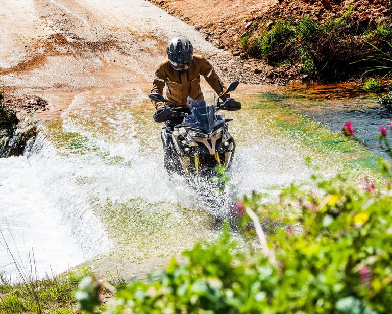 vyras, važiuojantis motociklu per vandens srovę