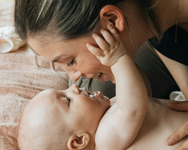 baby lying on his back, staring up at his mom's face smiling
