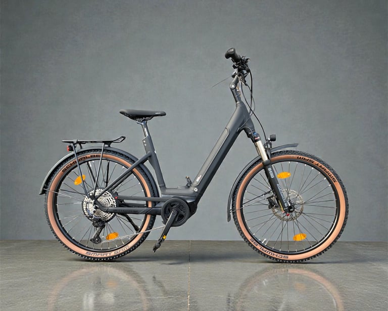 A modern black step-through electric bike with Schwalbe tan wall tires and a rear luggage rack.