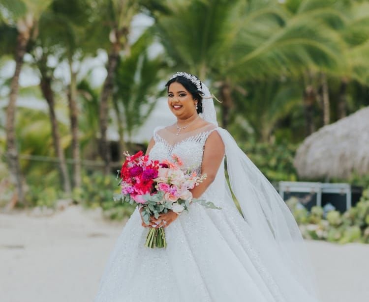 Beach bride in flowing gown holding colorful bouquet during tropical wedding