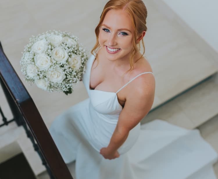 Elegant bride holding white rose bouquet after professional wedding hair and makeup
