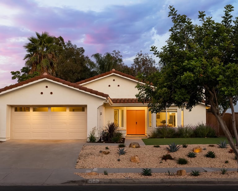 a white Spanish style house with a pink front door