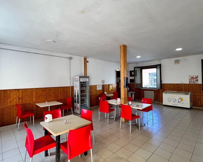 a bar with red chairs and tables and a refrigerator