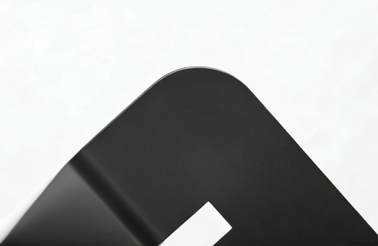Close-up of a rounded corner on a matte black metal frame with a smooth finish.