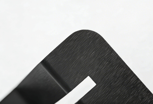 Close-up of a brushed black metal surface with a curved edge and smooth matte finish.