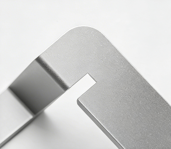 Close-up of a matte silver anodized aluminum bracket with a rounded corner and precision cutout.