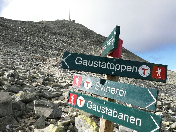 a directional sign with a mountain in the background-wikiloc site