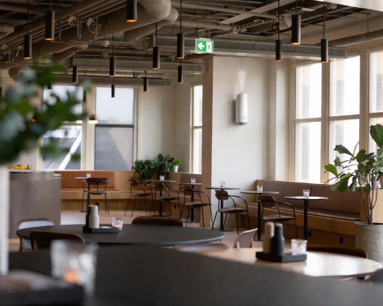 Área de descanso de una oficina moderna con techos industriales, mobiliario de cafetería minimalista