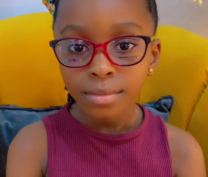 a young girl wearing glasses and a pink top