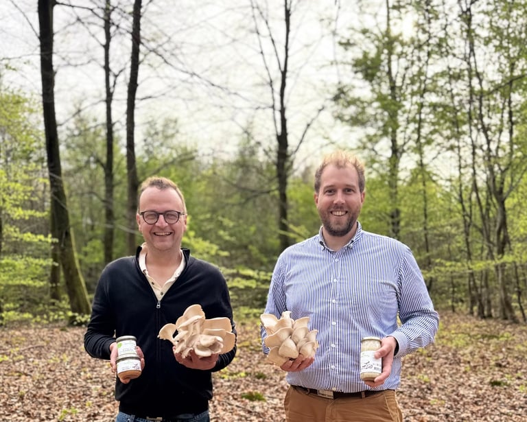 two men standing next to each other holding beer