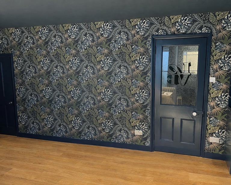 Sussex room featuring dark blue doors and tropical botanical wallpaper with palm leaf patterns.