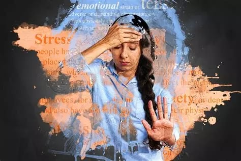 Femme, cheveux longs, main droite sur front, yeux fermés, main gauche en signe de rejet du stress