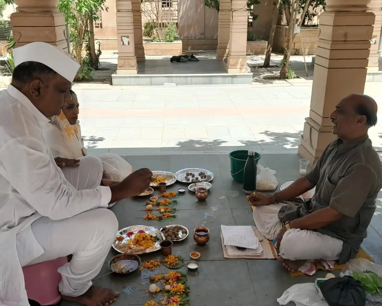 Elderly yajaman couple performing Matrugaya Shraddh Pooja with marigold offerings at Bindu Sarovar Siddhpur