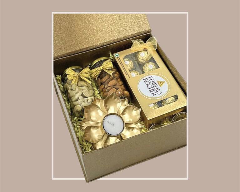 Golden box for festive gifting with Ferrero Rocher, dry fruits, and a t-light holder.