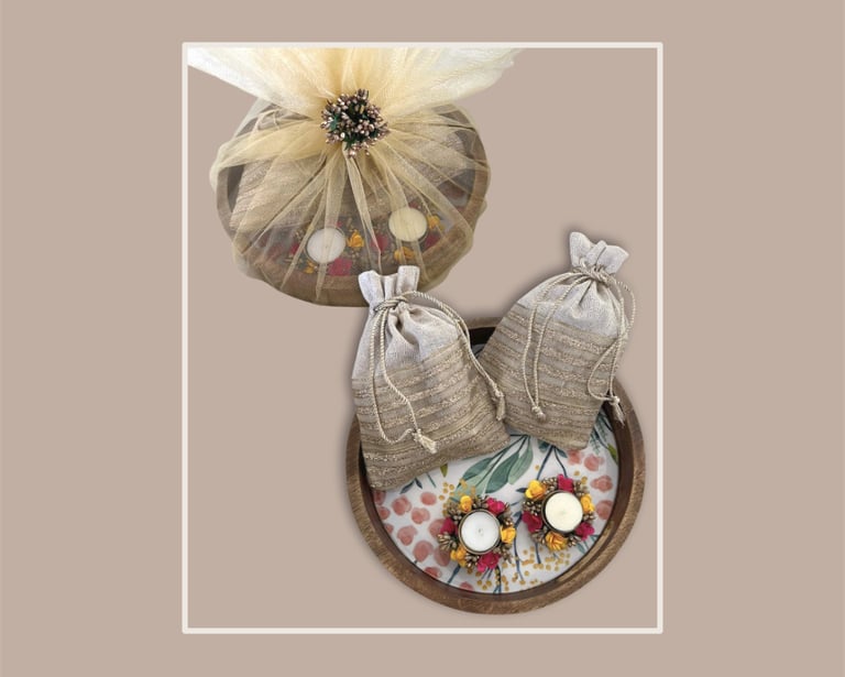 Circular festive gifting tray with silver shimmer potlis and floral accents.
