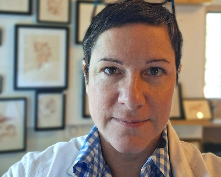 portrait d'Alex Corkish dans son atelier, avec en fond les estampes qu'elle produit