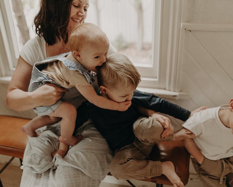 a woman holding a baby and two children