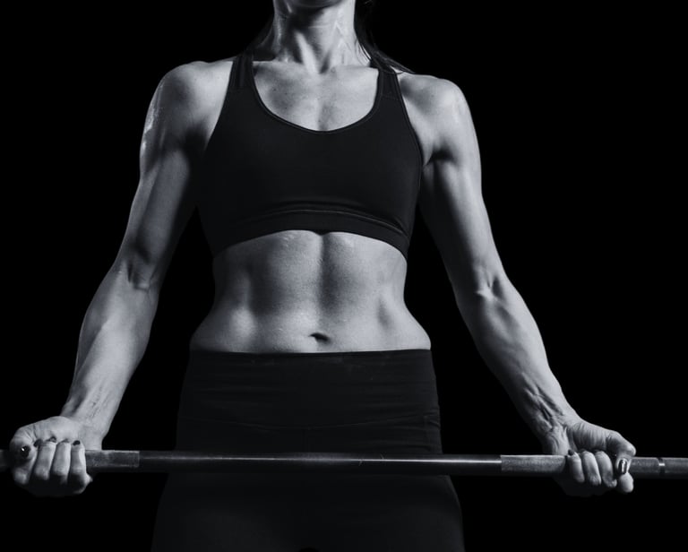 Femme sportive en tenue d’entraînement soulevant une barre, représentant un programme de coaching structuré et un suivi série
