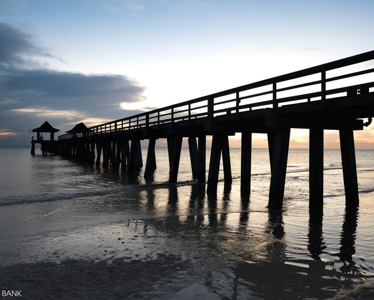 shadowy sunset view of naples pier in naples florida, with waves and the ocean and clouds 