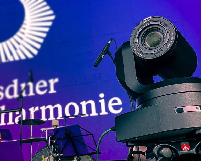 Professionelle Videokamera auf Bühne mit Giesinger Harmonie-Logo.