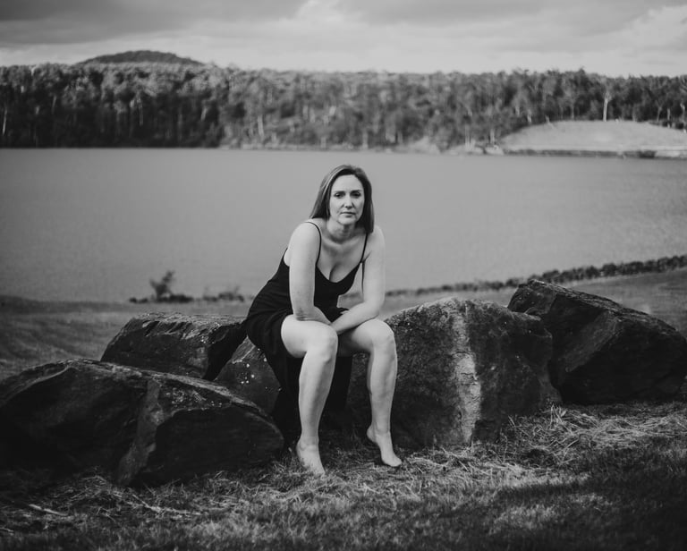 a woman sitting on a rock next to a lake