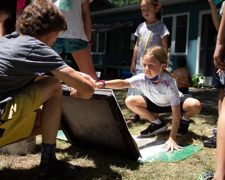 Teacher holding up a screen for papermaking in front of one of our youth students.