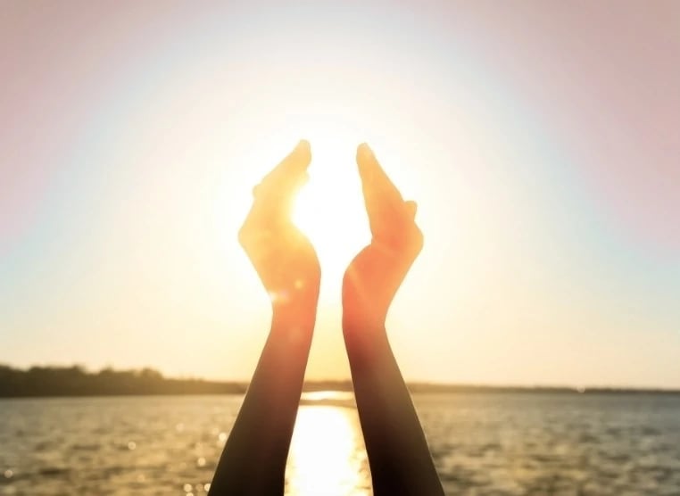 Des mains tendues vers le soleil, symbolisant l'espoir et la connexion avec la lumière.