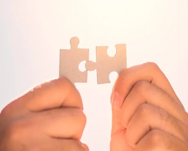 Deux mains s'apprêtent à assembler deux pièces de puzzle, représentant la collaboration et la recherche de solutions.