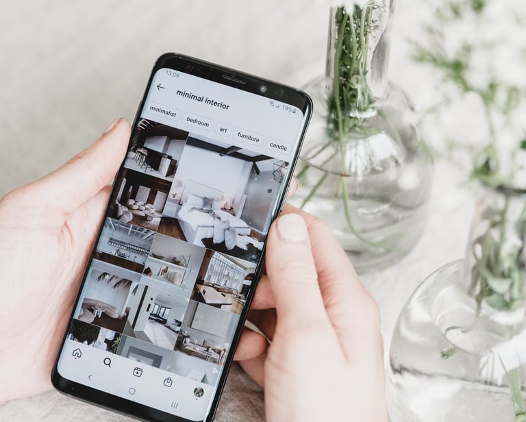 a person holding a phone with a camera and a vase with flowers
