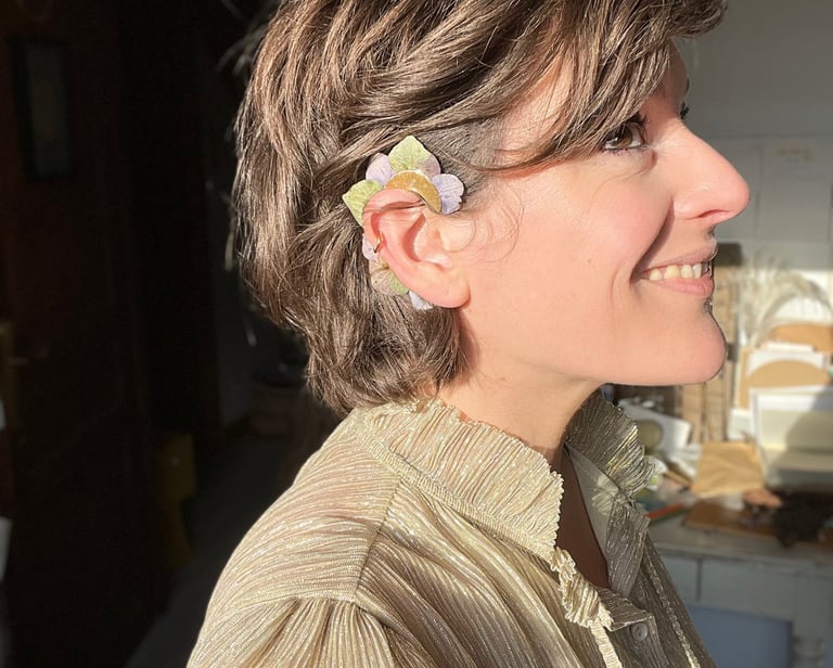 portrait de la créatrice Charlie O'Plumes portant un earcuff en pétales d'hortensia dans son atelier